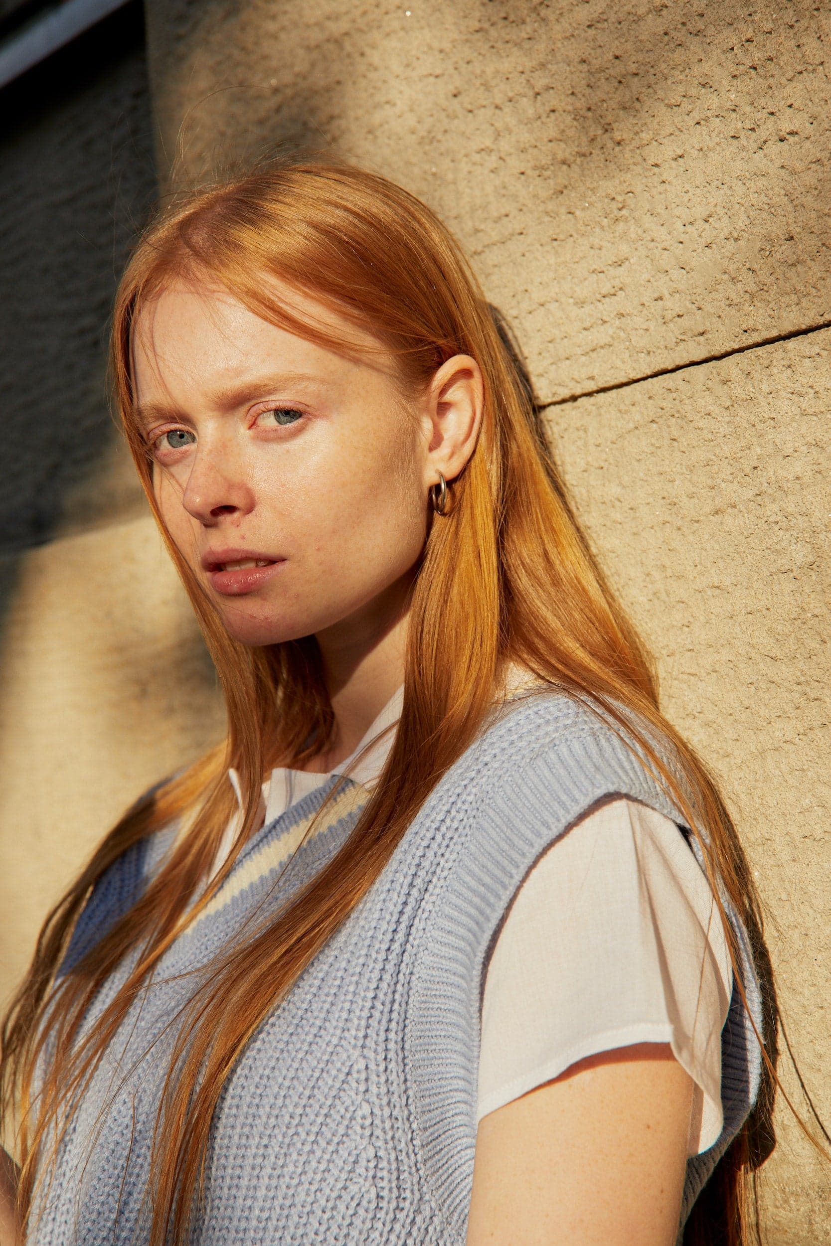 Une femme rousse avec un pull bleu clair