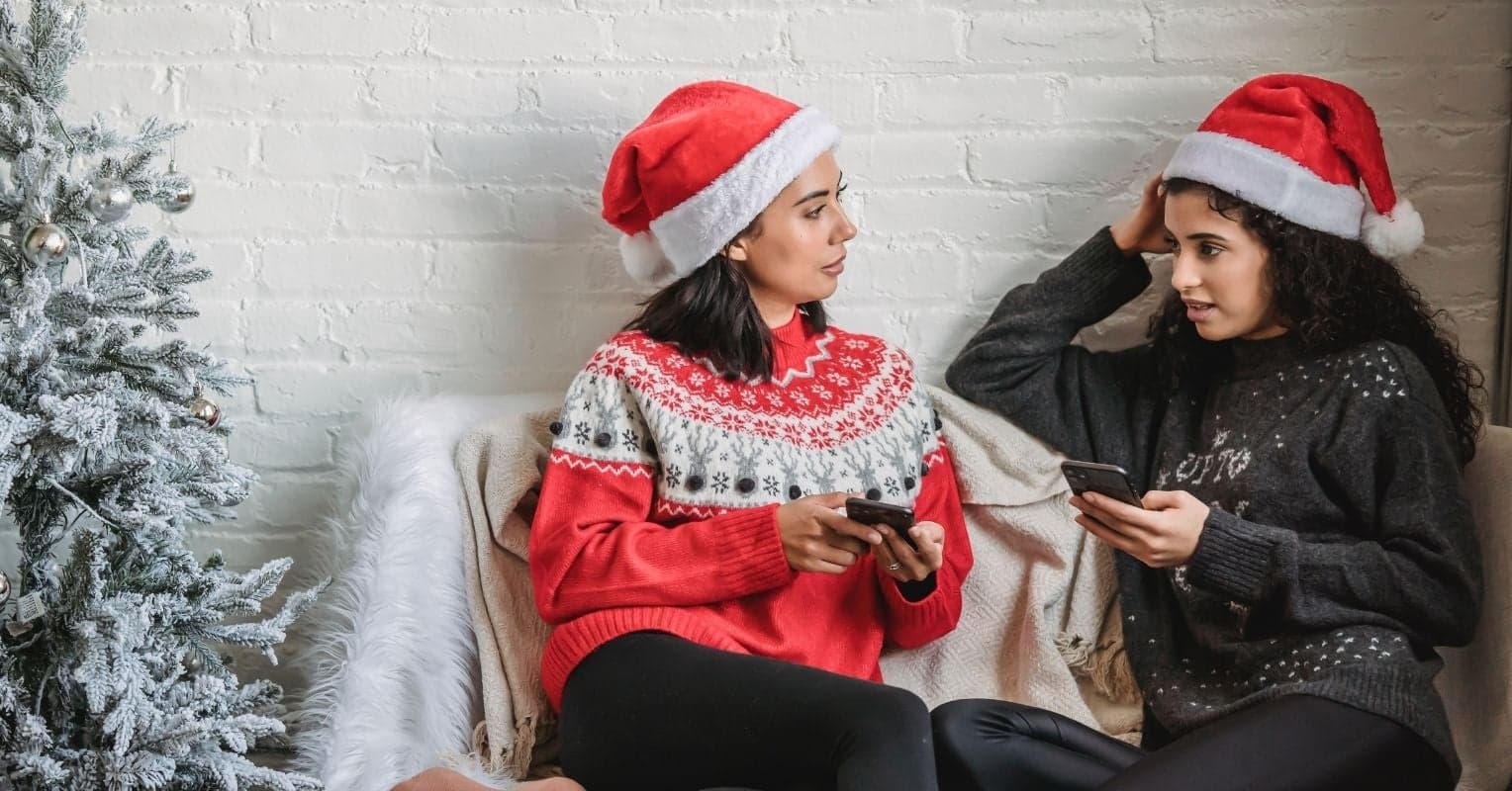 Deux femmes assises avec des bonnets de Père Noël sur la tête