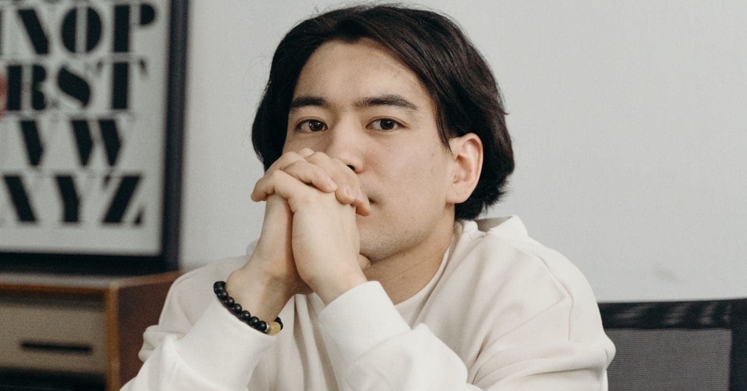 A man with a white sweater and joined hands