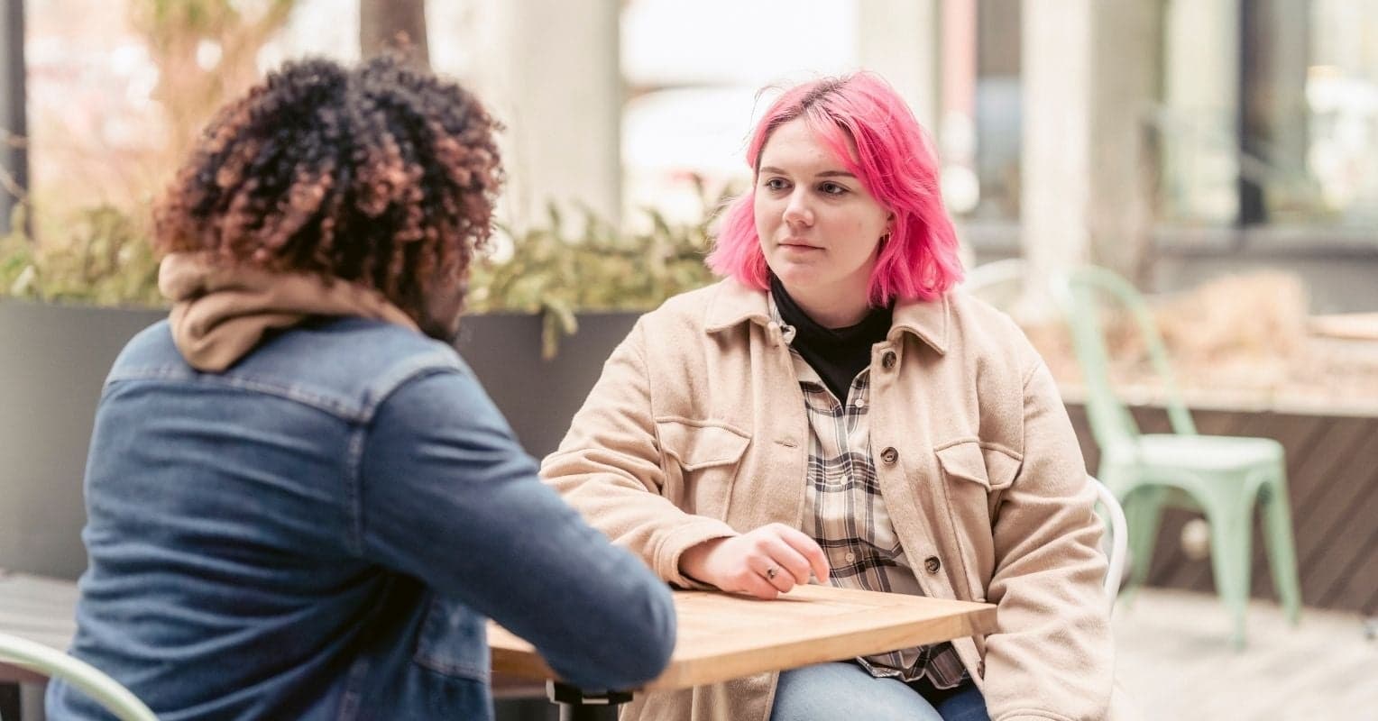 A woman with pink hair talking to a man