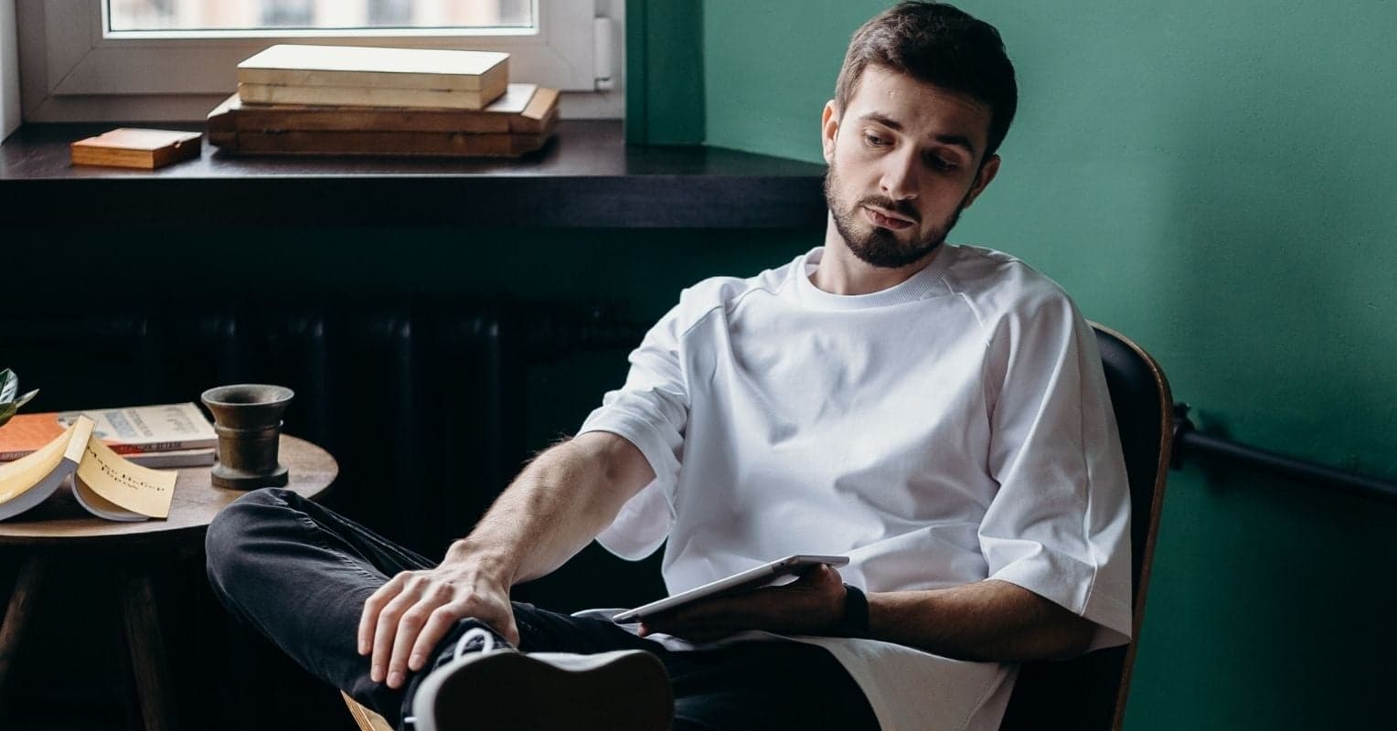 A man with a white shirt seating on a chair