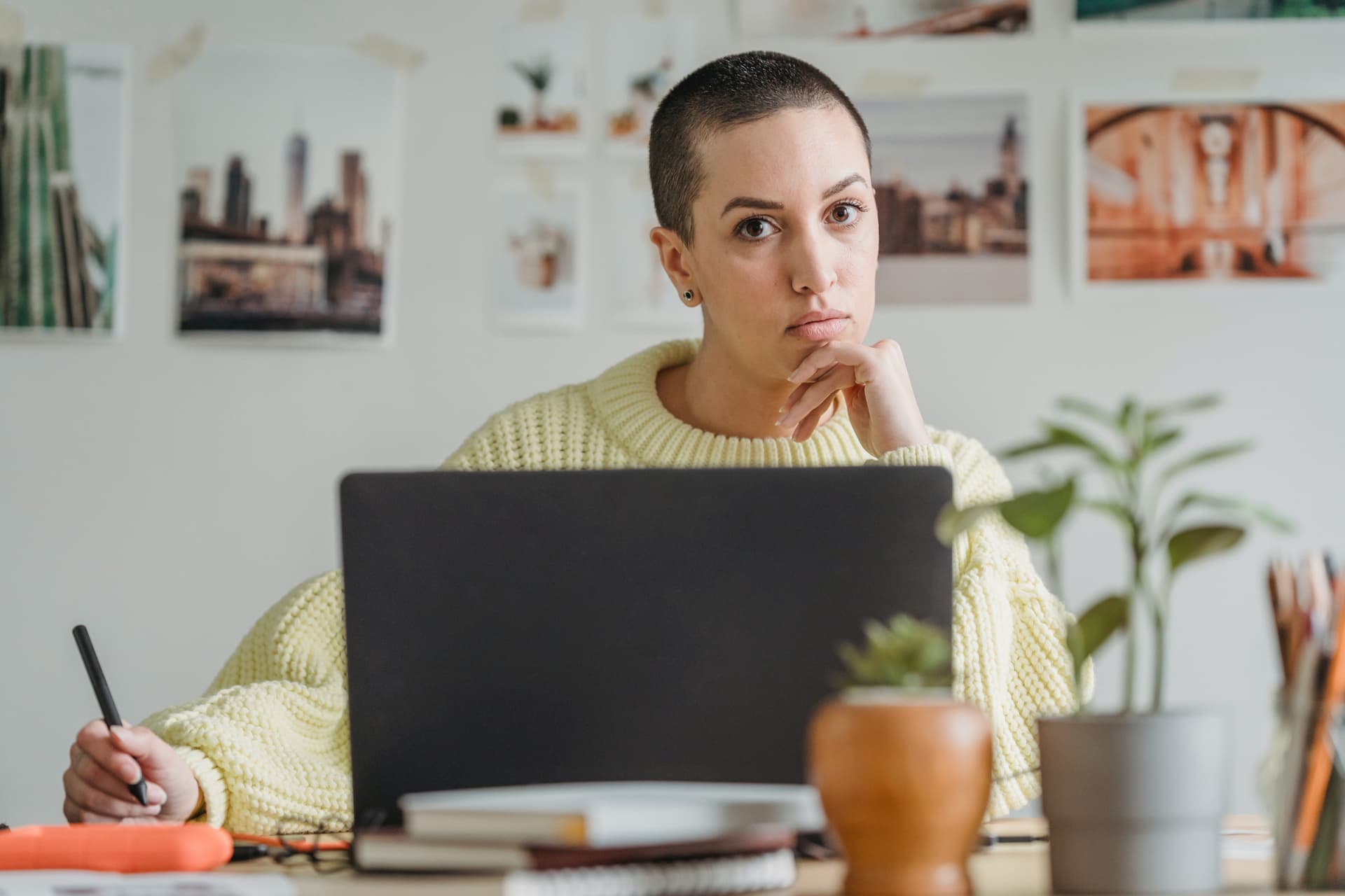 Une femme avec les cheveux courts et un pull jaune devant son ordinateur portable