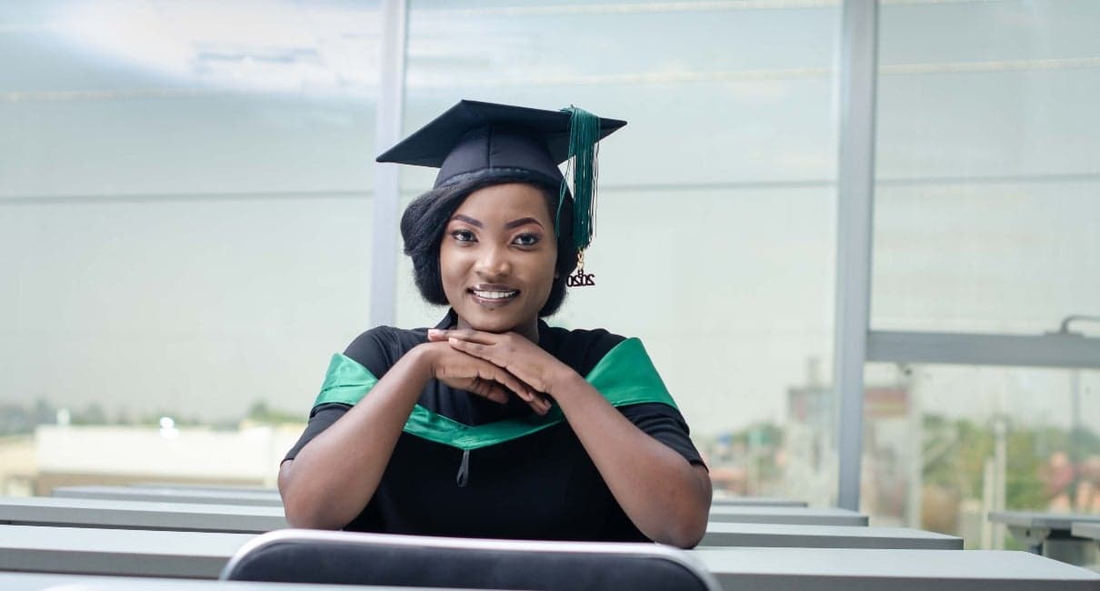 A woman sitting at a desk and smiling after having graduated