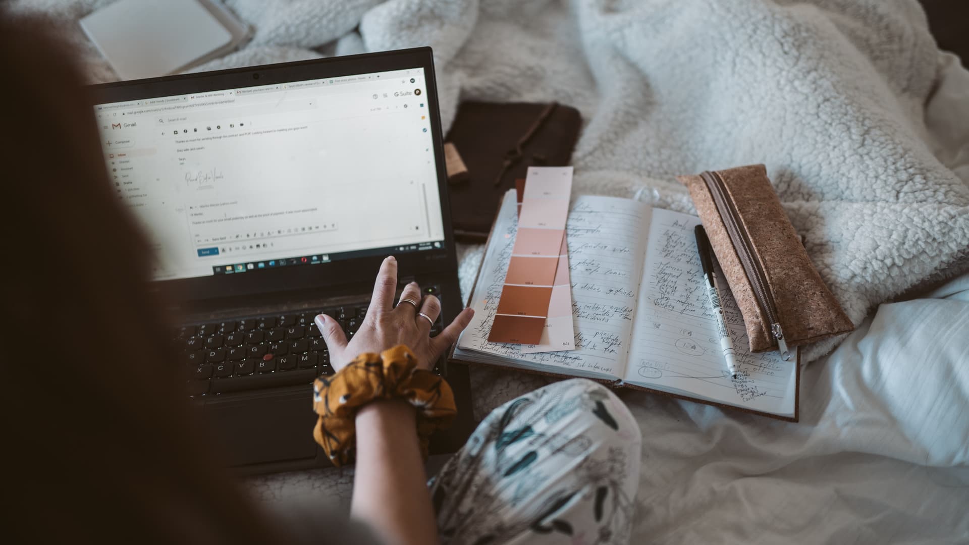 Frau sitzt auf Bett und schreibt E-Mail