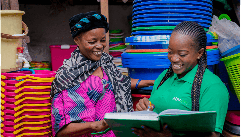 Cliente d'Advans en RDC (Congo) devant son stand au marché, avec sa chargée de clientèle