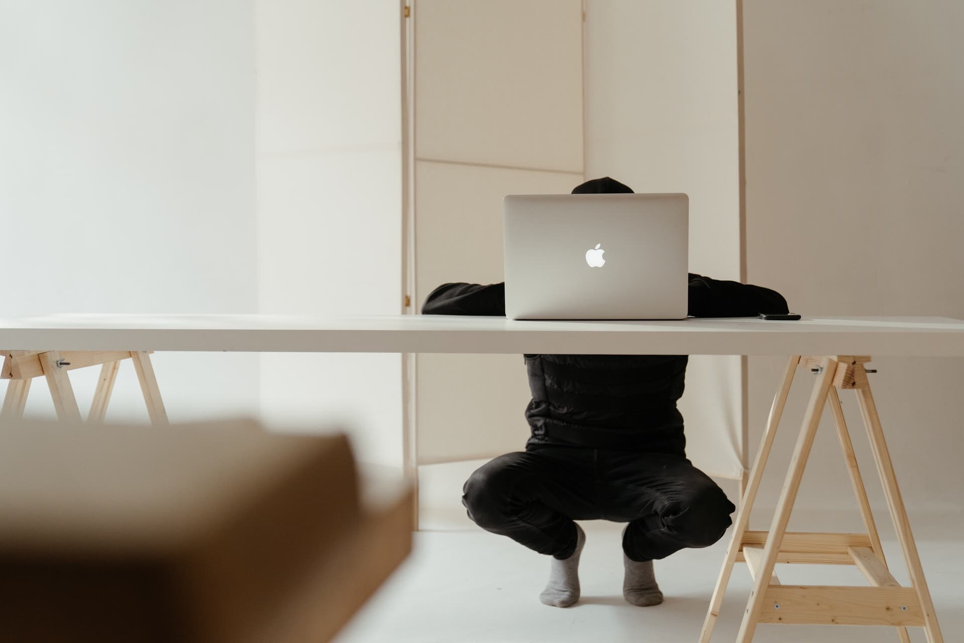 Un homme accroupi devant une table de bureau