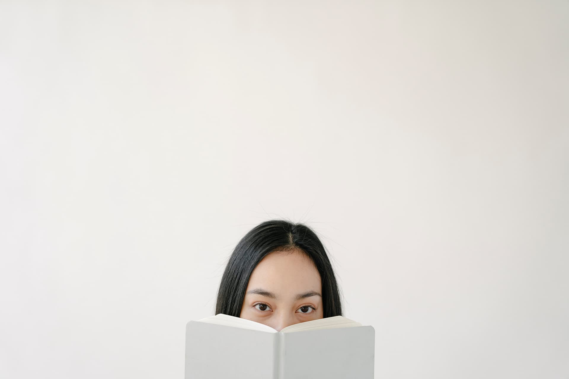 Une femme qui se cache le visage derrière un livre