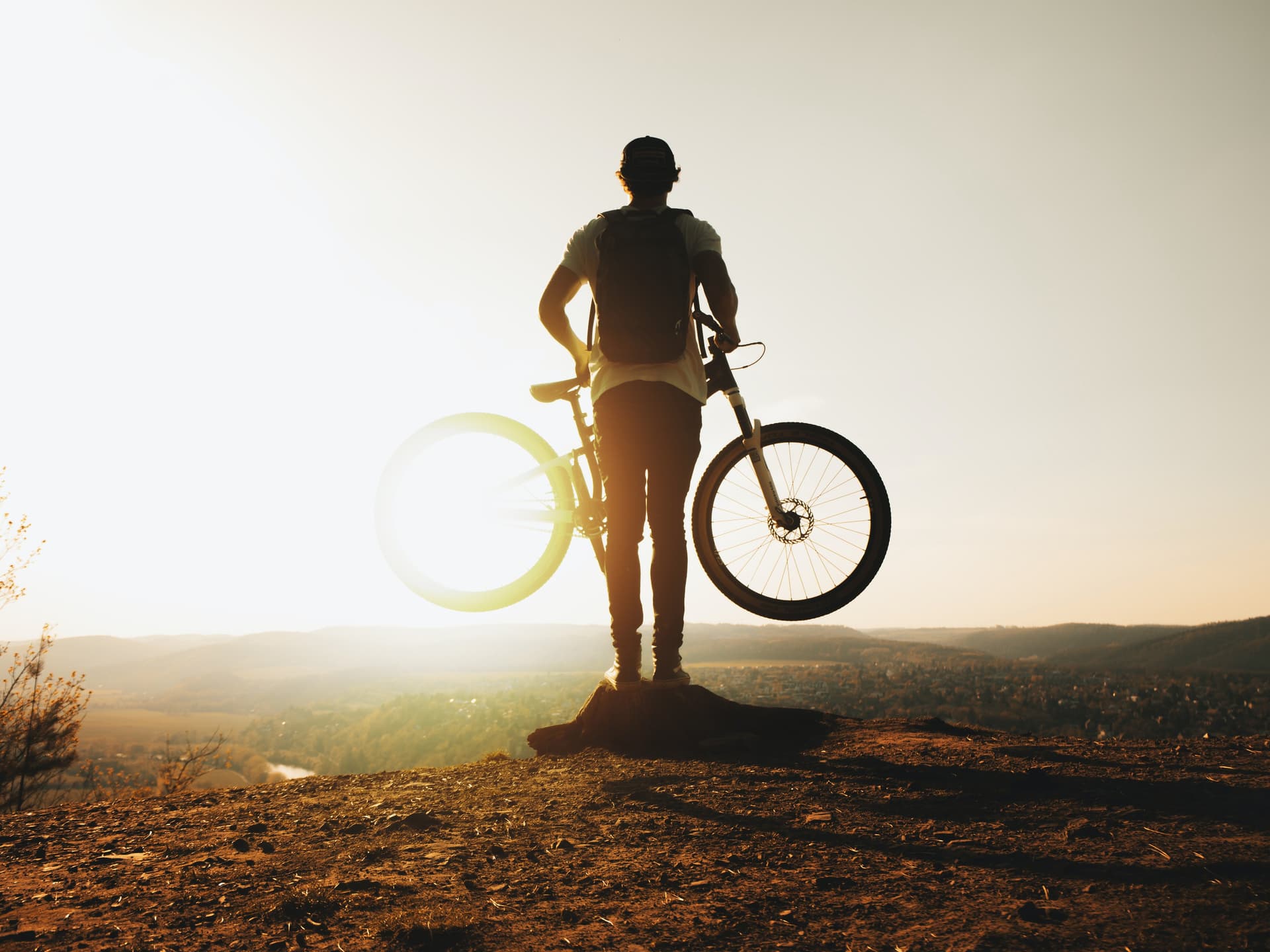 Un cycliste portant son vélo devant un coucher de soleil
