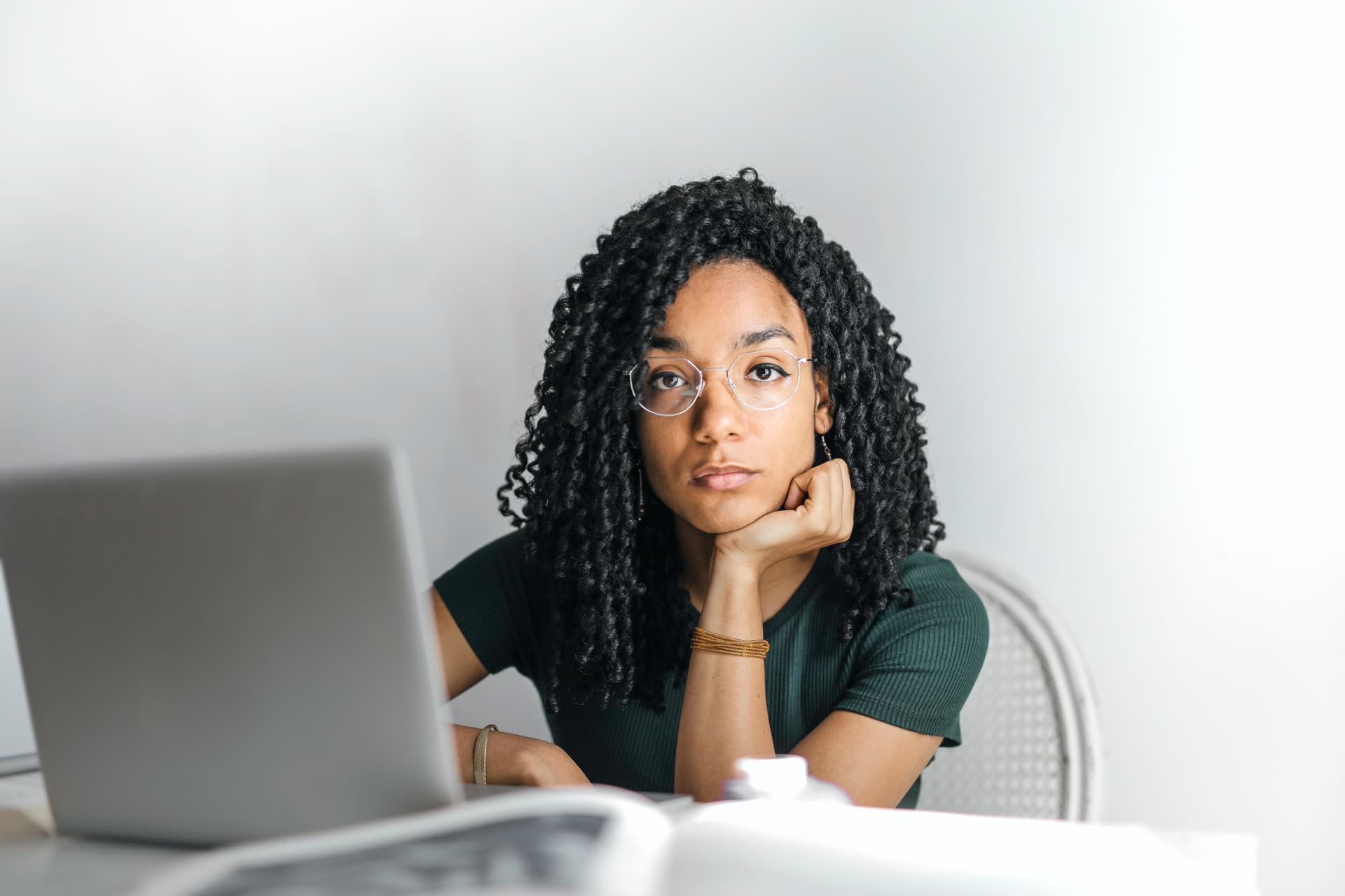 Een vrouw met een bril die voor haar PC zit