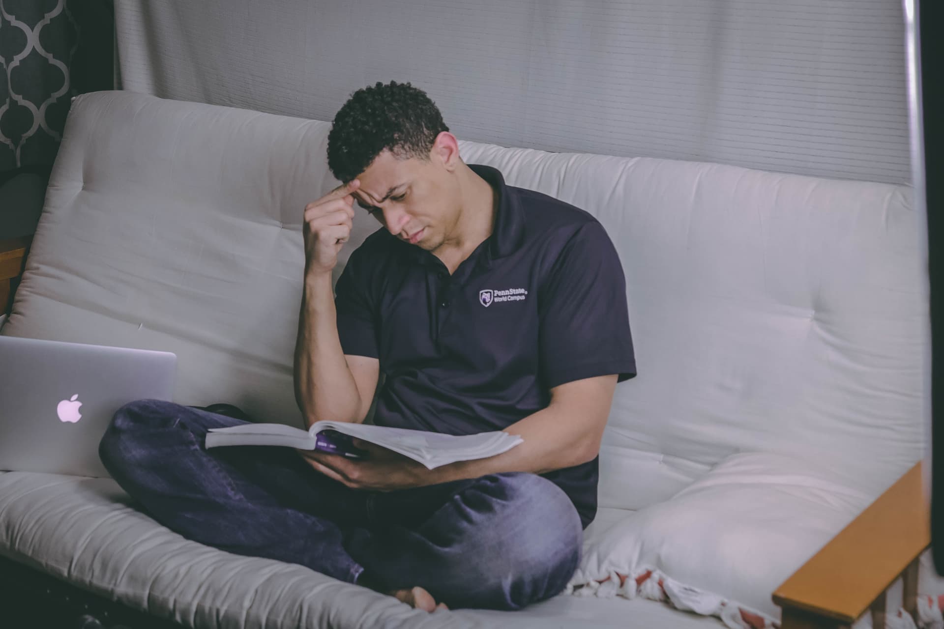 Mann sitzt mit Buch auf Sofa