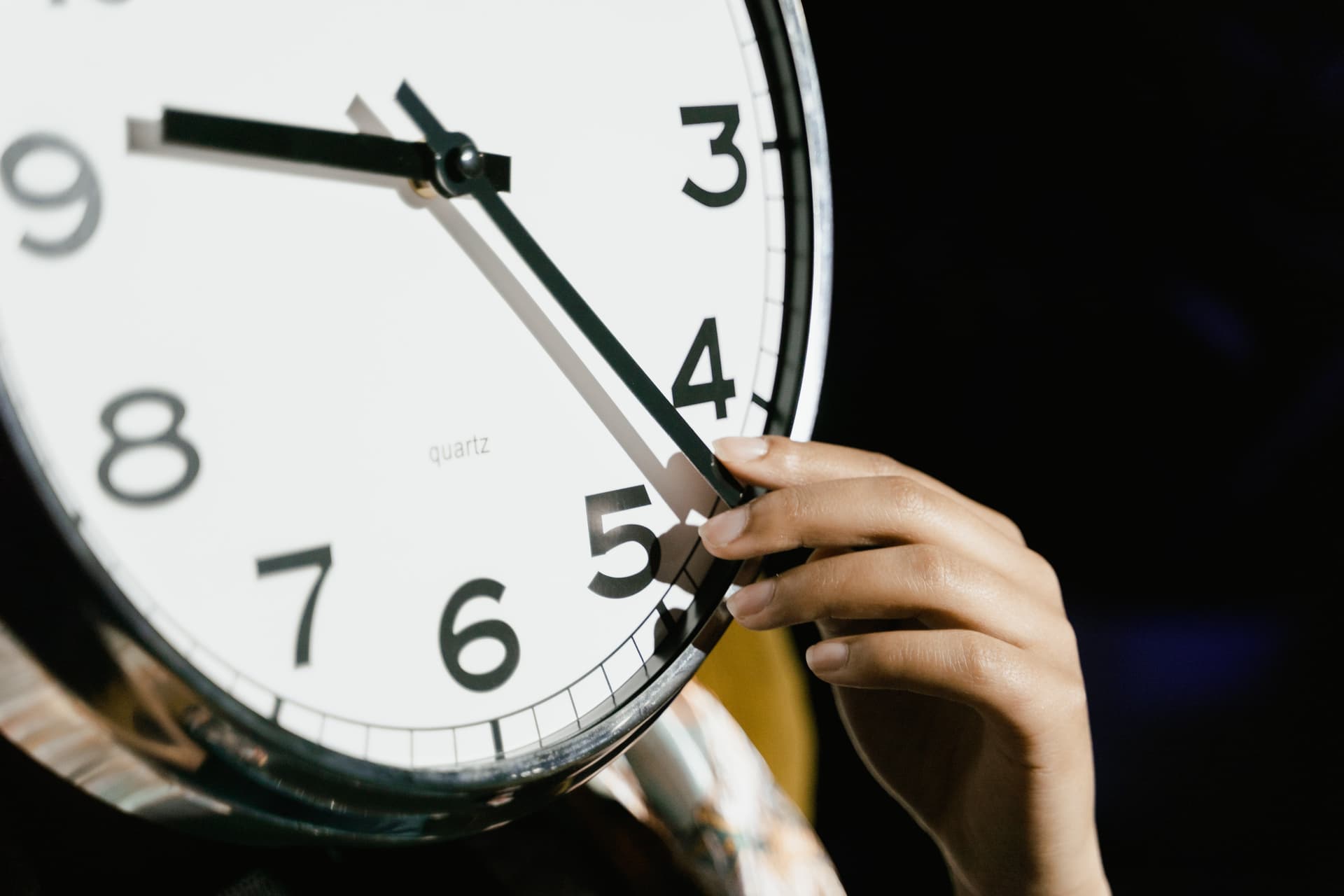 Hand dreht an einer Uhr