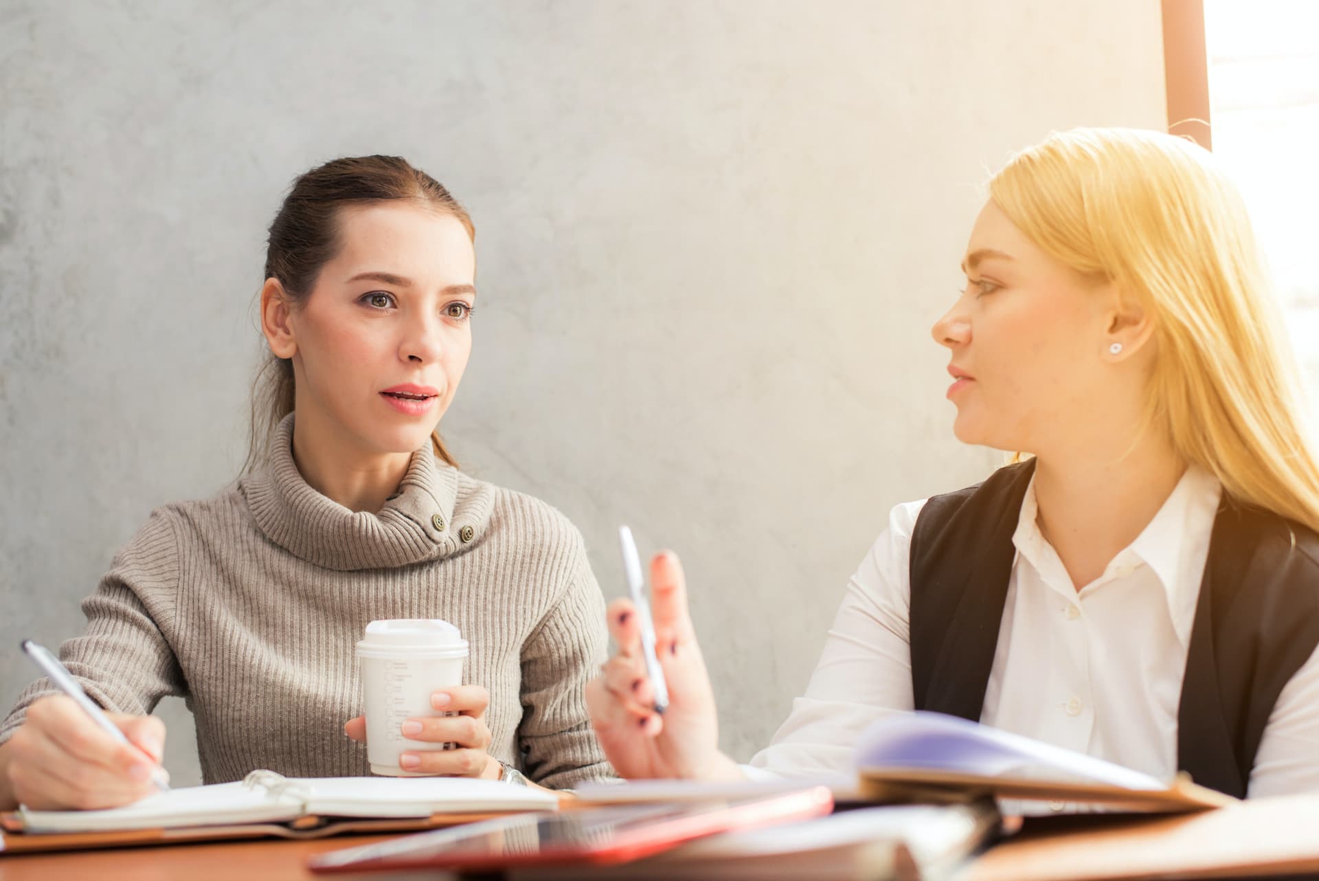 Zwei Frauen sitzen an einem Tisch und sprechen