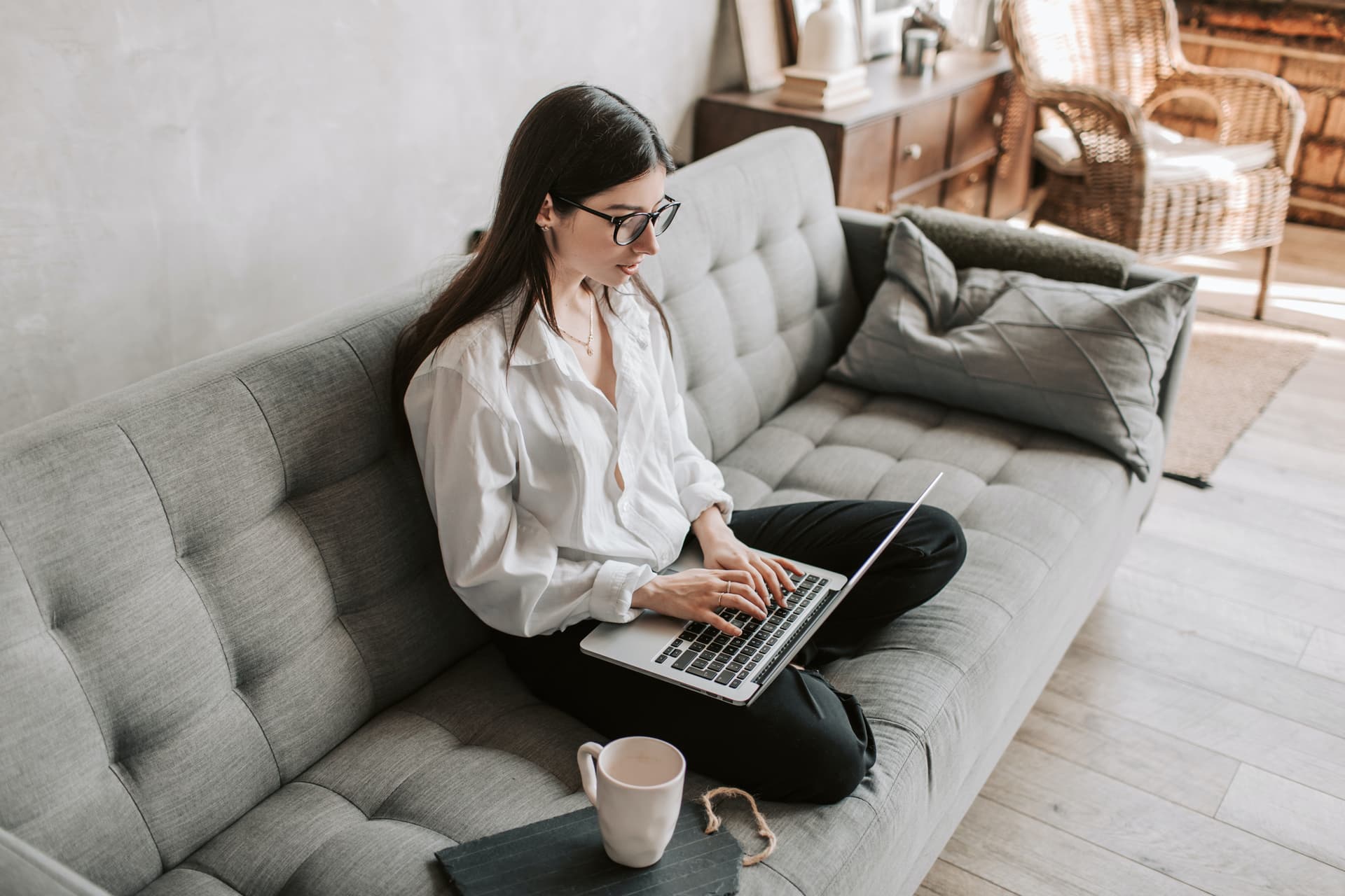 Junge Frau sitzt mit Laptop auf Sofa